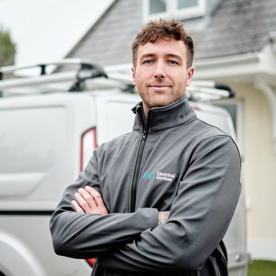 Scott McClurg of MC Electrical, in branded workwear beside the company van